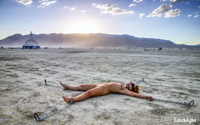 "Securely exposed" Dee Luvbight at Burning Man 2004, chained to the playa, blindfolded and gagged.